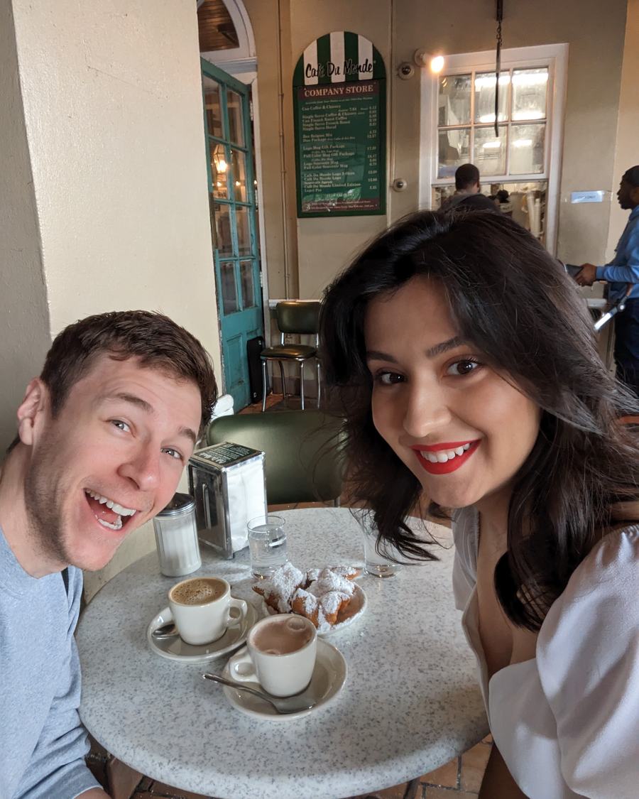 Megan and Tyler at a café table with coffee and beignets