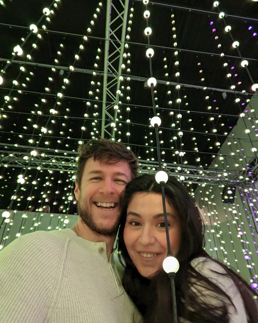 Megan and Tyler smiling under strings of lights