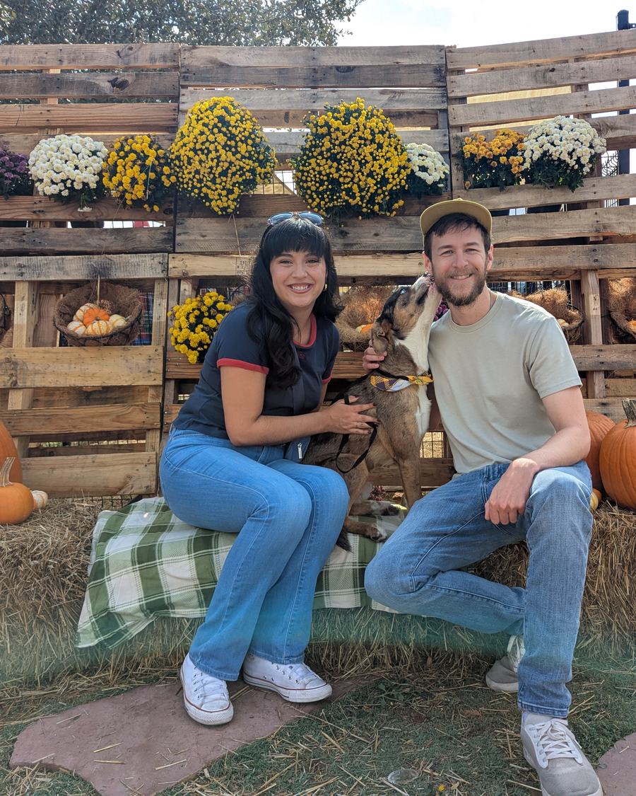 Megan and Tyler sitting on hay bales beside a pumpkin display